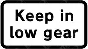 Keep in Low Gear Sign – Diagram 526. Official UK road sign advising drivers to engage a lower gear on steep hills and tight bends for improved safety and vehicle control.